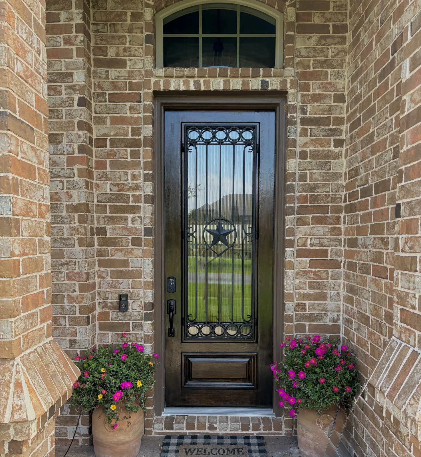 Refinished dark front door framed by brick and planters