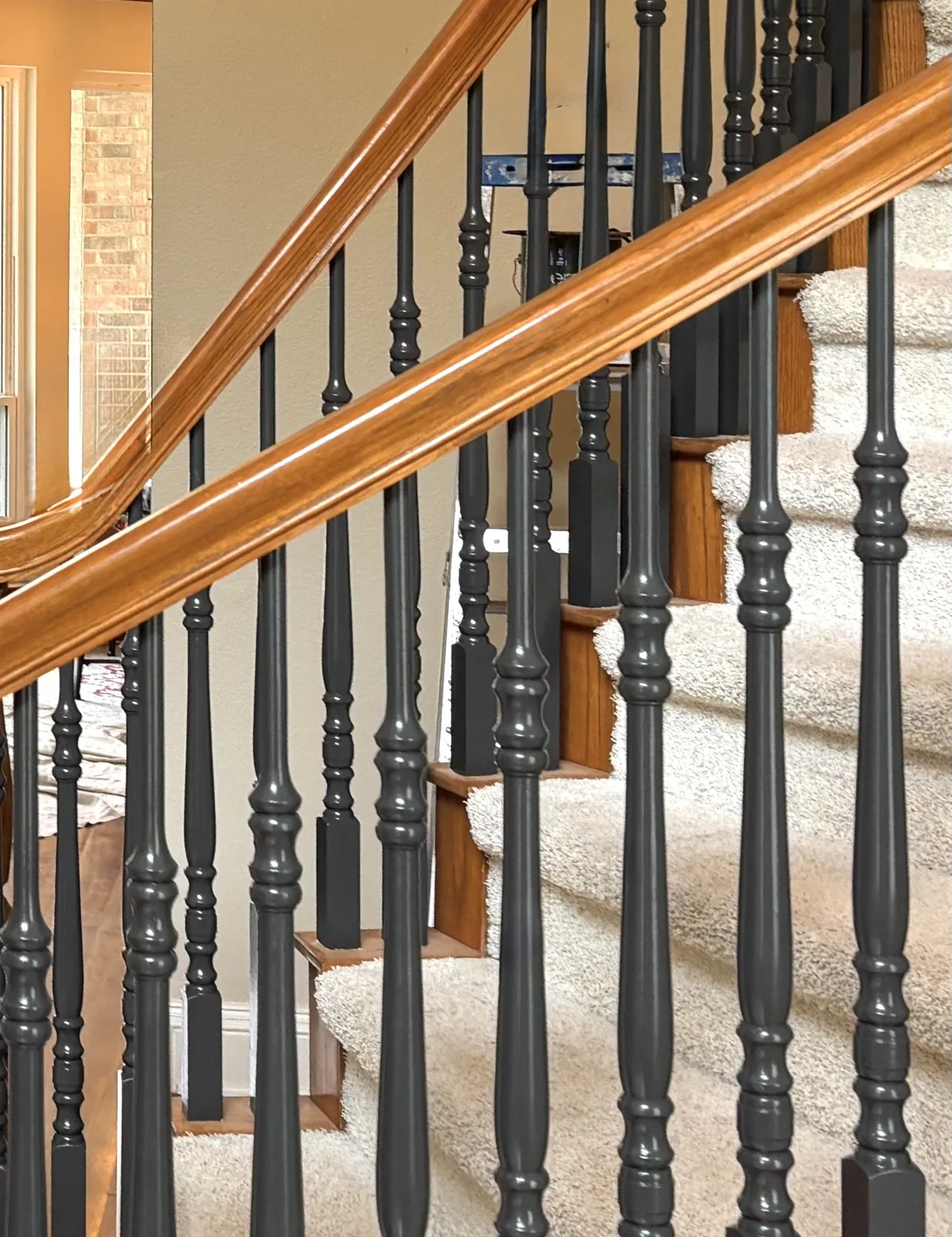 Dark painted stair balusters beside a warm wood handrail