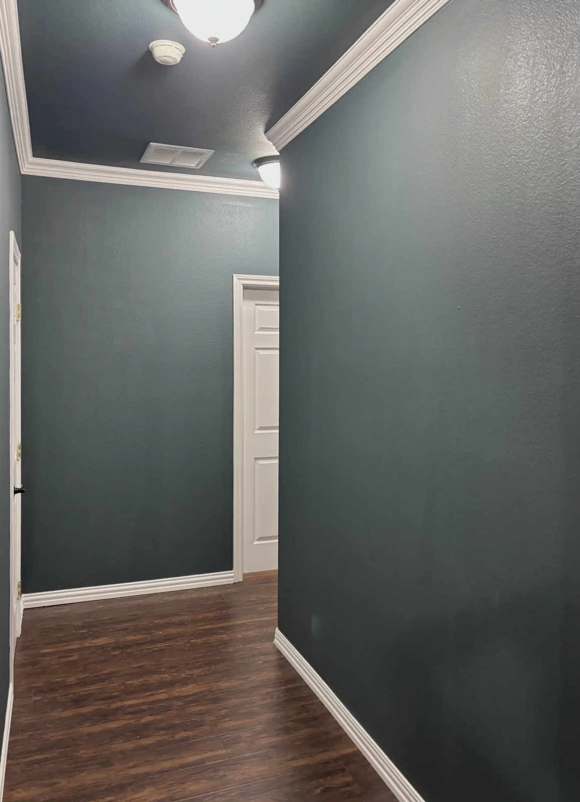 Deep green hallway walls with white crown molding and trim