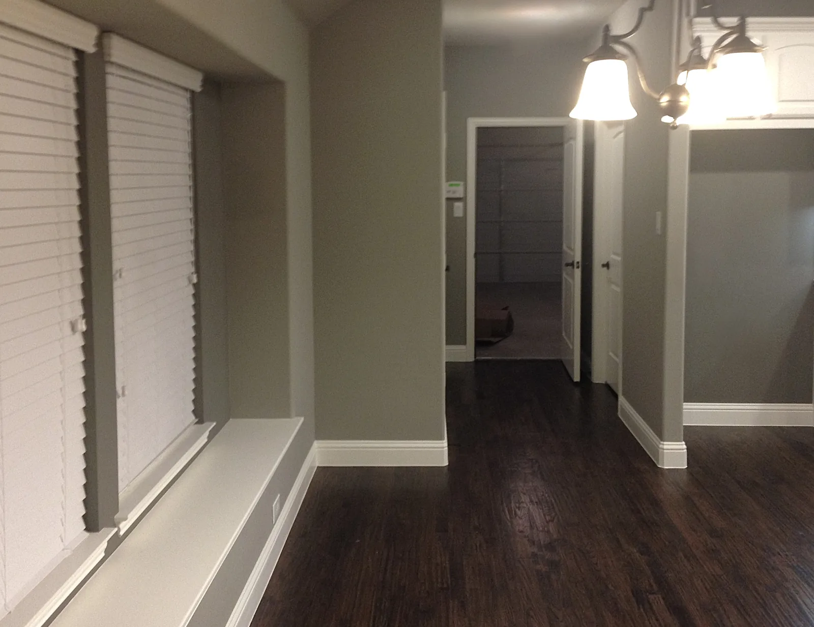 Finished hallway with warm gray walls, white trim, and dark wood flooring