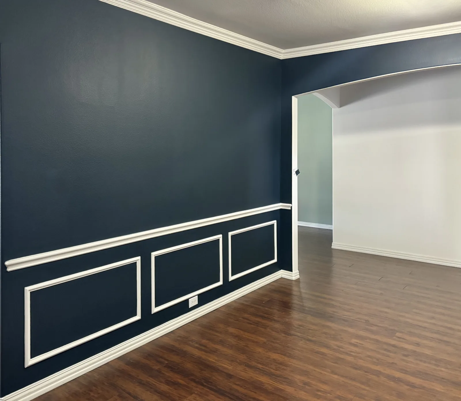 Deep blue painted walls with white crown molding and picture-frame trim